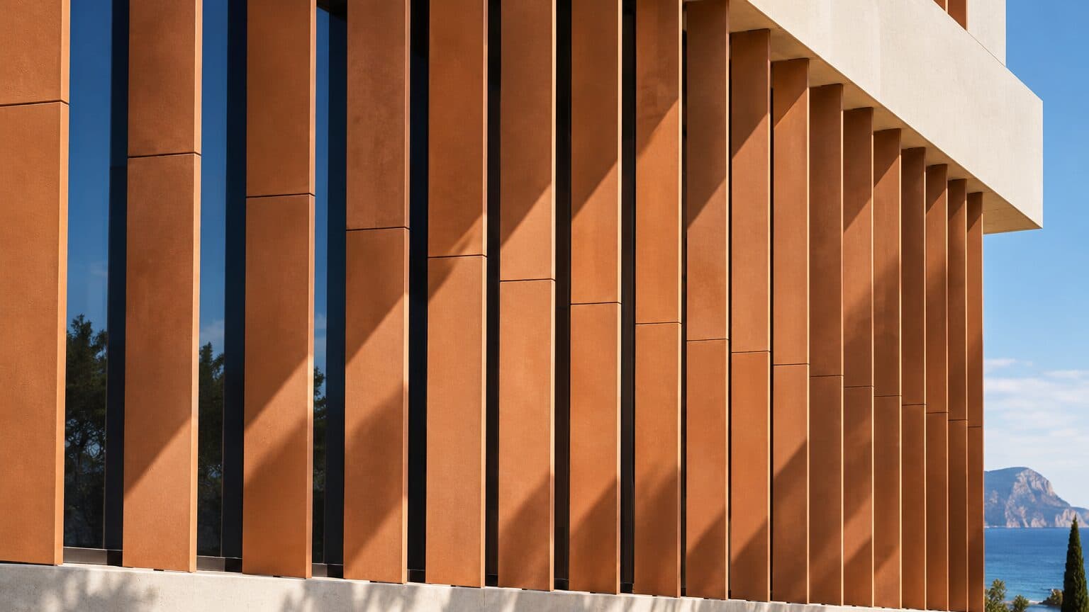 A geometric terracotta and steel structure under raking light